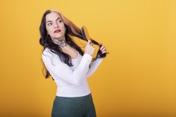 Woman combing her hair over yellow background.