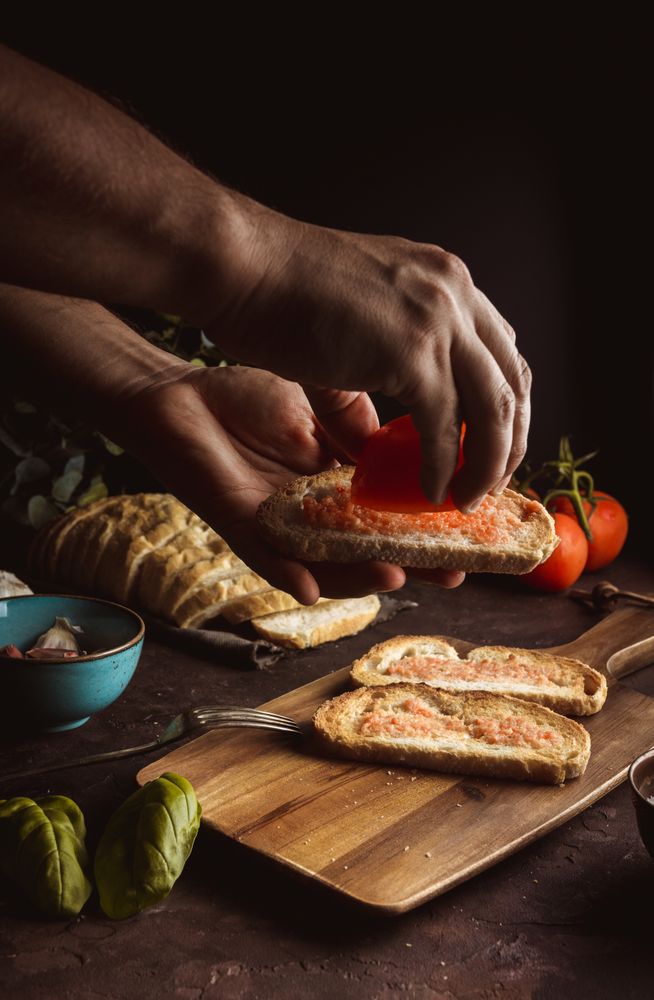 Crop person pouring tomato on toasts