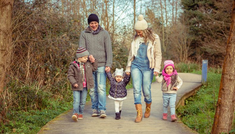 Happy family of five walking along path in forest