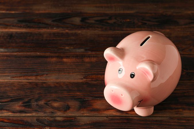 Happy piggy bank on wooden background, space for text. Finance, saving money