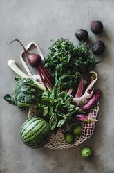 Mesh bag overflowing with fresh produce, top view, vertical composition