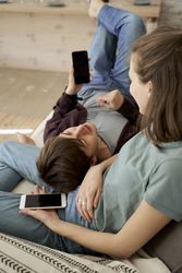 Chilling couple spending time together on sofa browsing smartphone