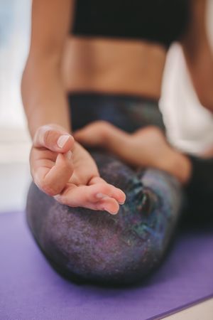 Close up of woman’s hand sitting in lotus pose indoors