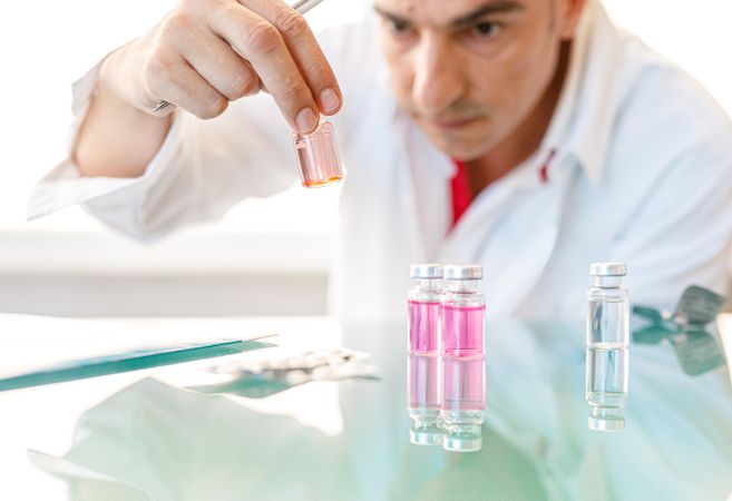 Man in white lab coat studying sample