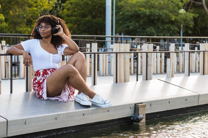 Black woman listening to music near water
