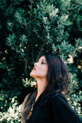 Smiling female looking out of green bushes