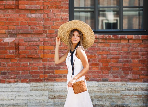 Woman outside a building in summer dress and sun hat