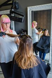 Hairdresser with protective gloves combing hair of woman