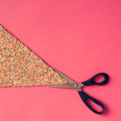 Scissors with sprinkles on pink background