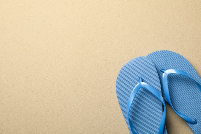 Flip flops on sea sand background, space for text