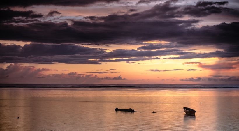 Boat and rocks under colorful dawn