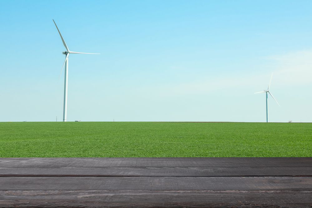 Wooden table against field with windmills. Agriculture concept. Mockup