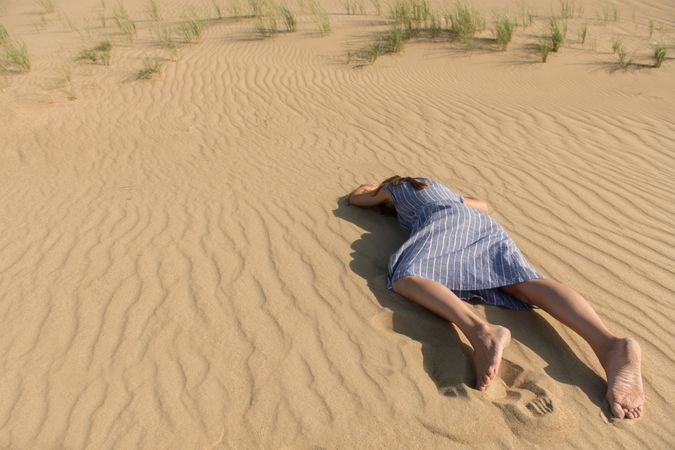 Young woman lying down on sand dune