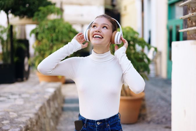 Joyful young woman enjoying the bliss of outdoor music while wearing her headphones