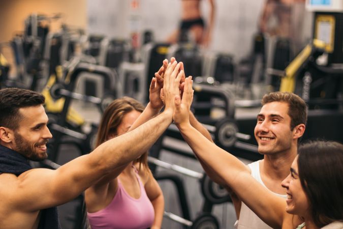 group of friends in a gym shaking hands. teammates, unity, group