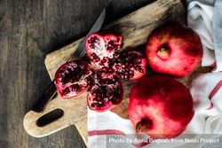 Fresh cut pomegranate on breadboard with kitchen towel 43Glg4