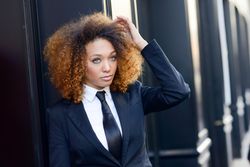 Female in suit outside adjusting her hair on street