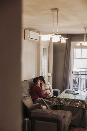 Couple expecting baby kissing at home