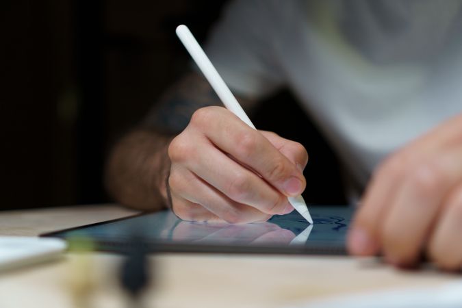 A young illustrator in white t-shirt creating illustration on a digital tablet