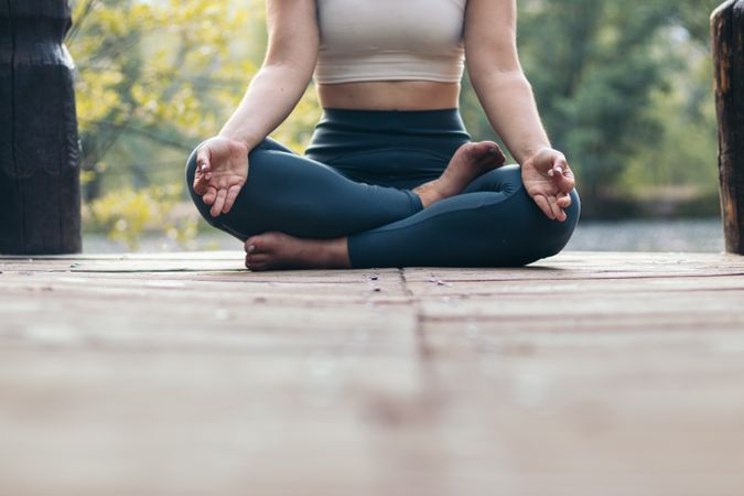 Woman meditating in nature near a lake
