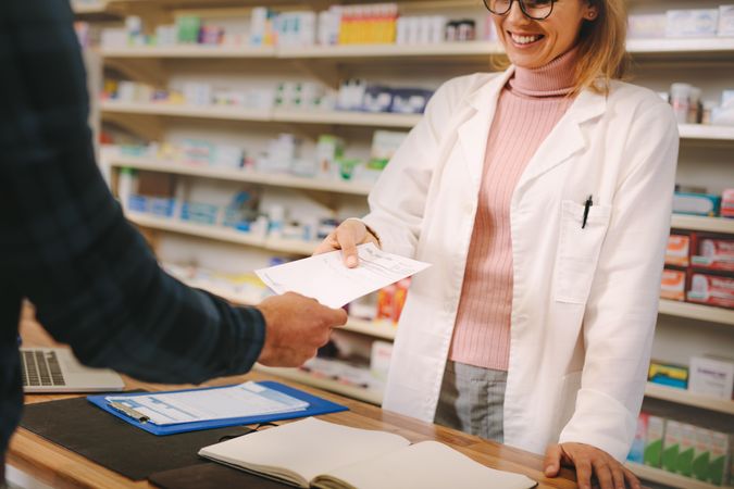 Female apothecary taking prescription from customer at pharmacy