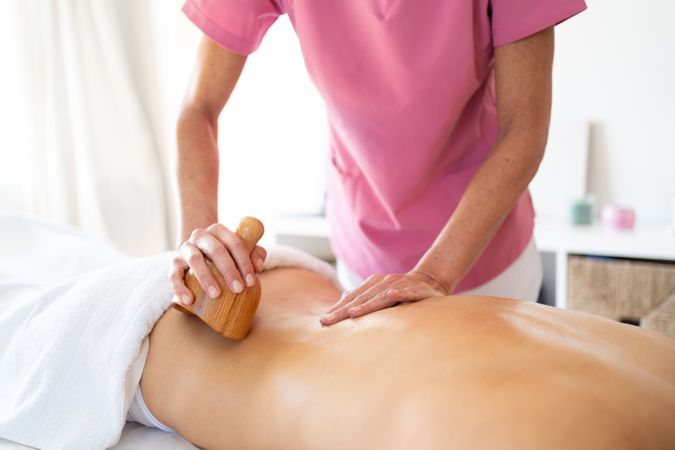 Masseuse kneading lower back of woman in spa