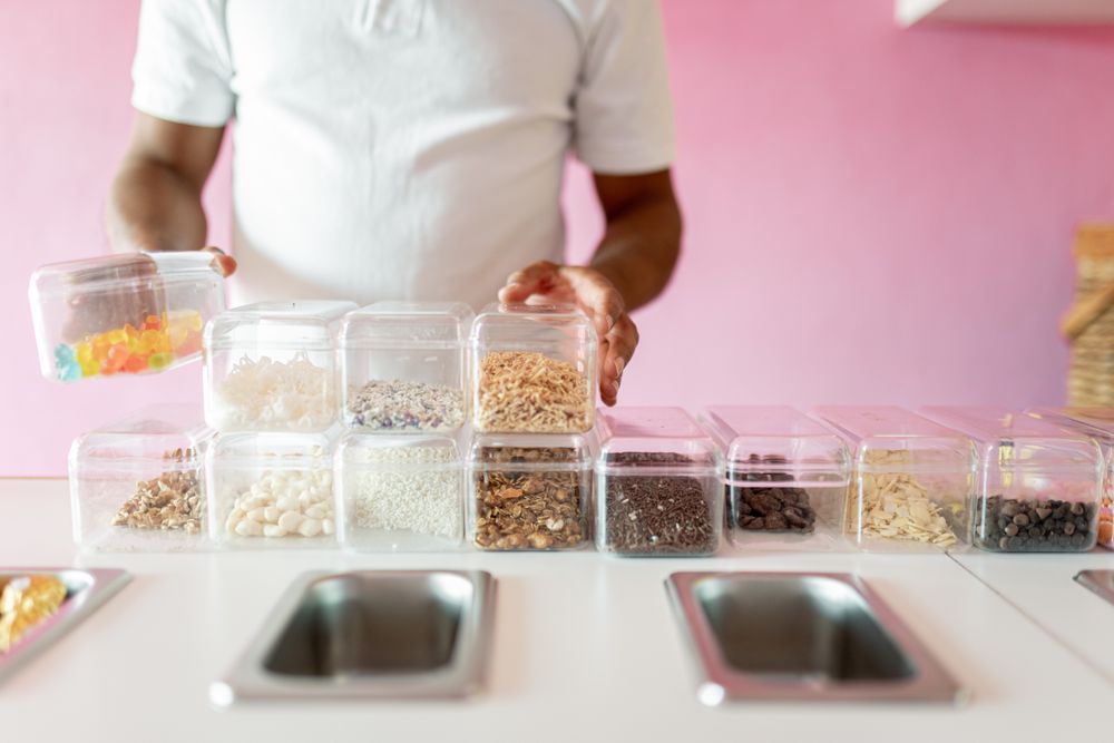 An ice-cream parlor worker is preparing all the toppings for the day on the counter
