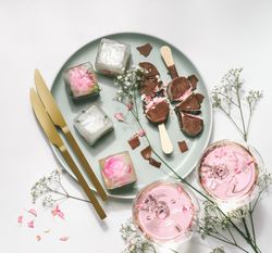 Ice cream popsicles with chocolate on plate with gypsophila,  wine glasses with rose wine, ice cubes and golden knifes