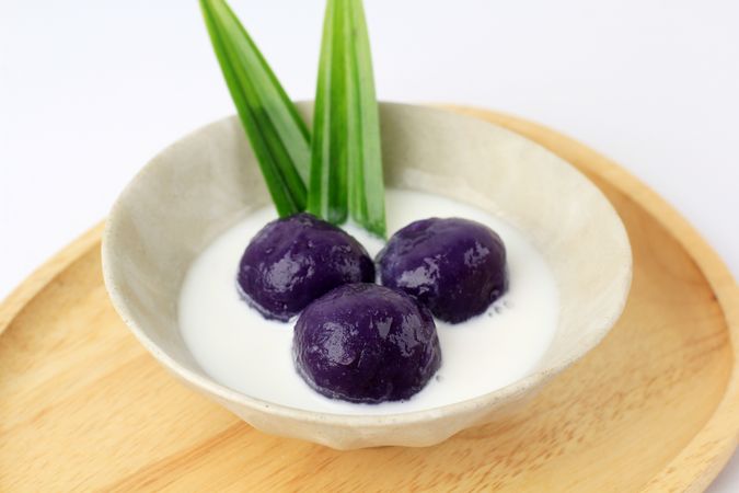 Purple sweet potato balls in bowl with coconut milk sauce