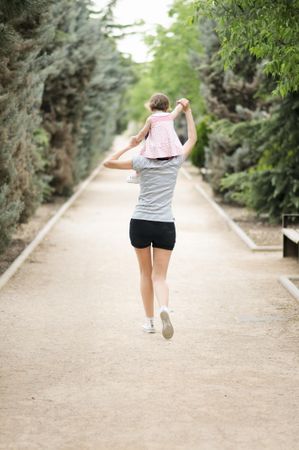 Woman in park with little girl on shoulder