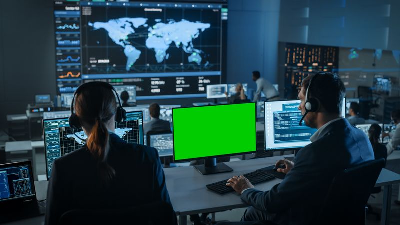Global Data Center With Analysts Monitoring Worldwide Activity. Large Screens Display World Map and Statistics.