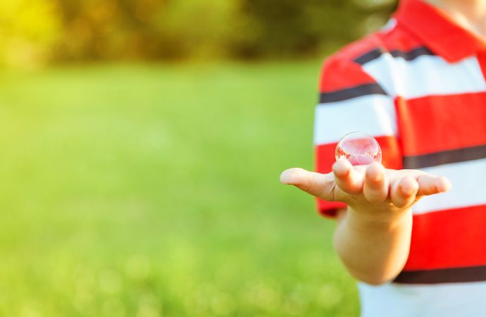 Cute boy showing soap bubble in his open hand