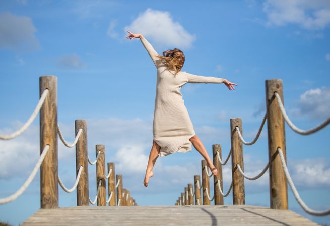 Woman with textile posing in air on footbridge