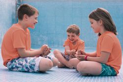 Children playing rock-paper-scissors in empty pool