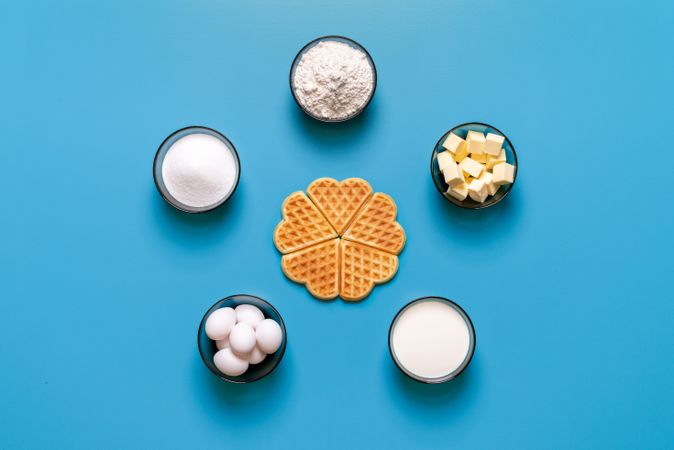 Waffle baking ingredients top view, isolated on a blue background
