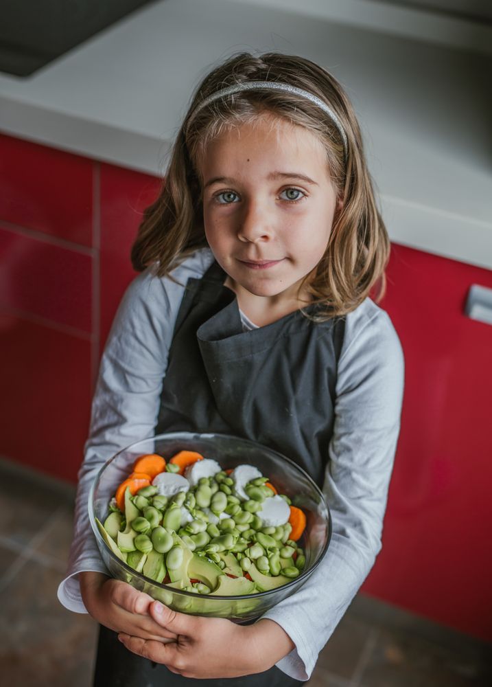 Girl with vegetable salad in kitchen