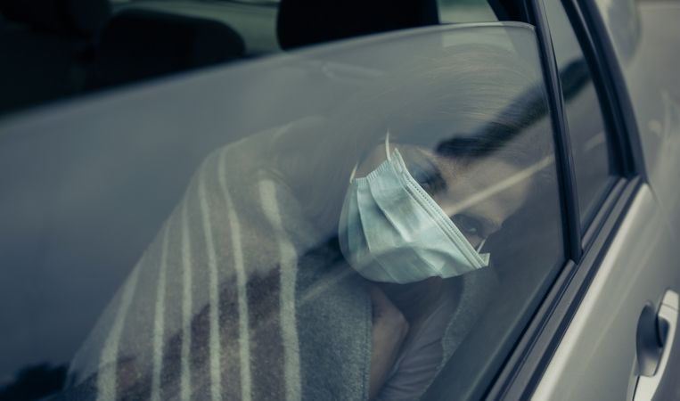 View through the car window of a woman with mask