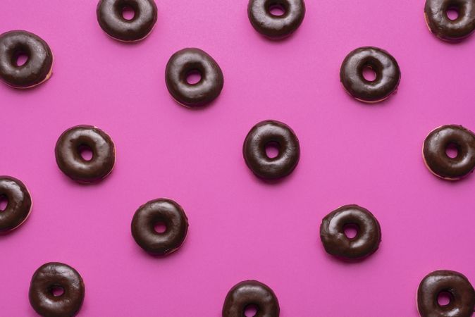 Donuts glazed  with chocolate aligned on a pink background