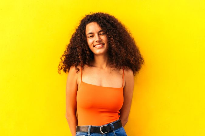 afro latina woman portrait leaning on a yellow wall