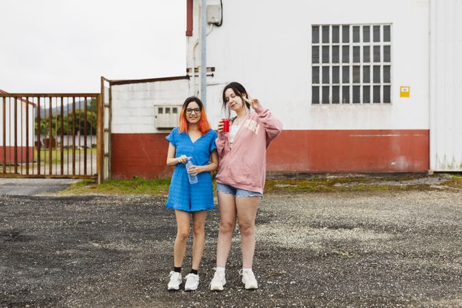Two young women sipping soda and stretching their legs during a stop on a road trip in a car