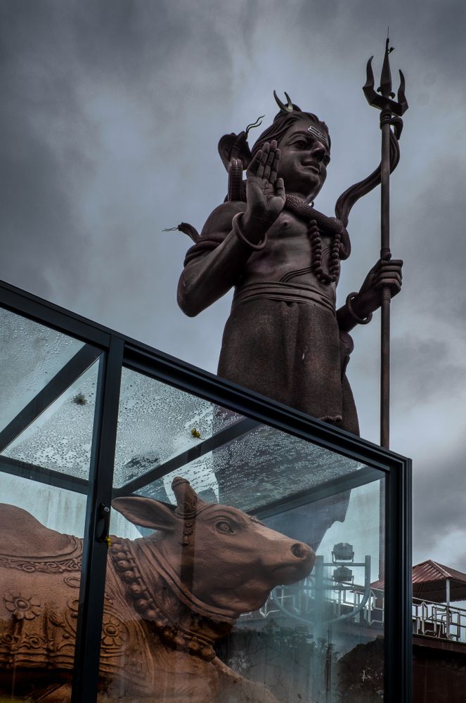 Statue of Shiva on cloudy day with cow underneath