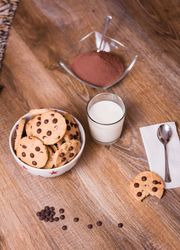 Chocolate chip cookies and milk on wood background