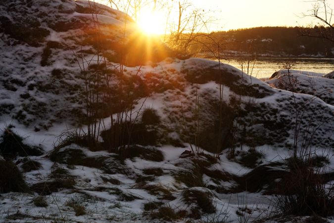 Rocky peaceful shore with snow crust in sunrays