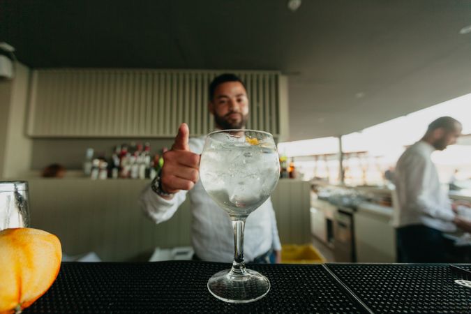 Cheerful Barman preparing alcoholic drinks in a bar with thumb up
