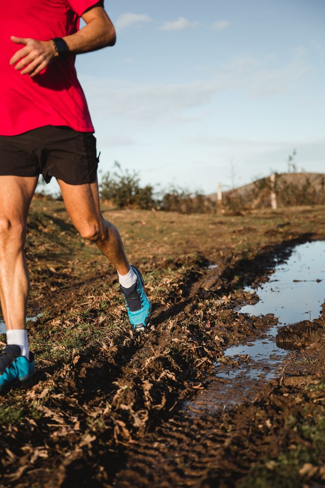 Sportsman running on dirty road in countryside
