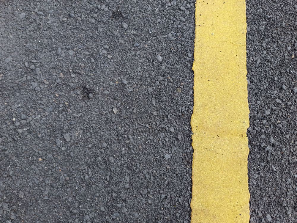 Asphalt road texture with yellow dividing line.