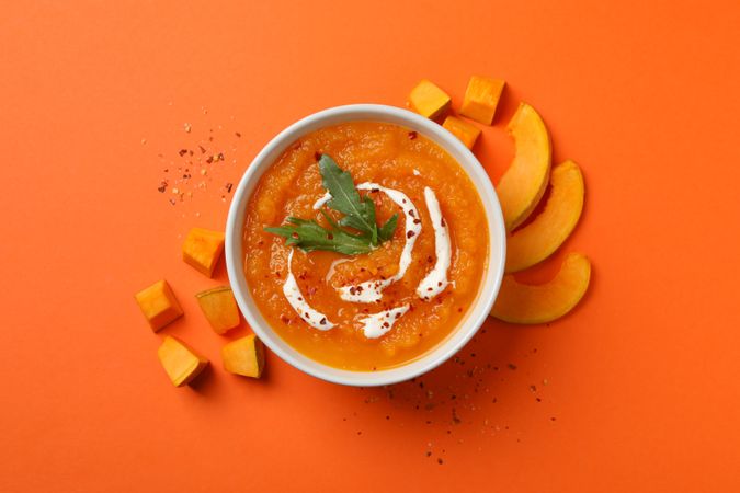 Top view of bowl of pumpkin soup on orange table