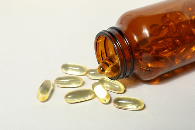 Brown bottle with omega pills on plain background