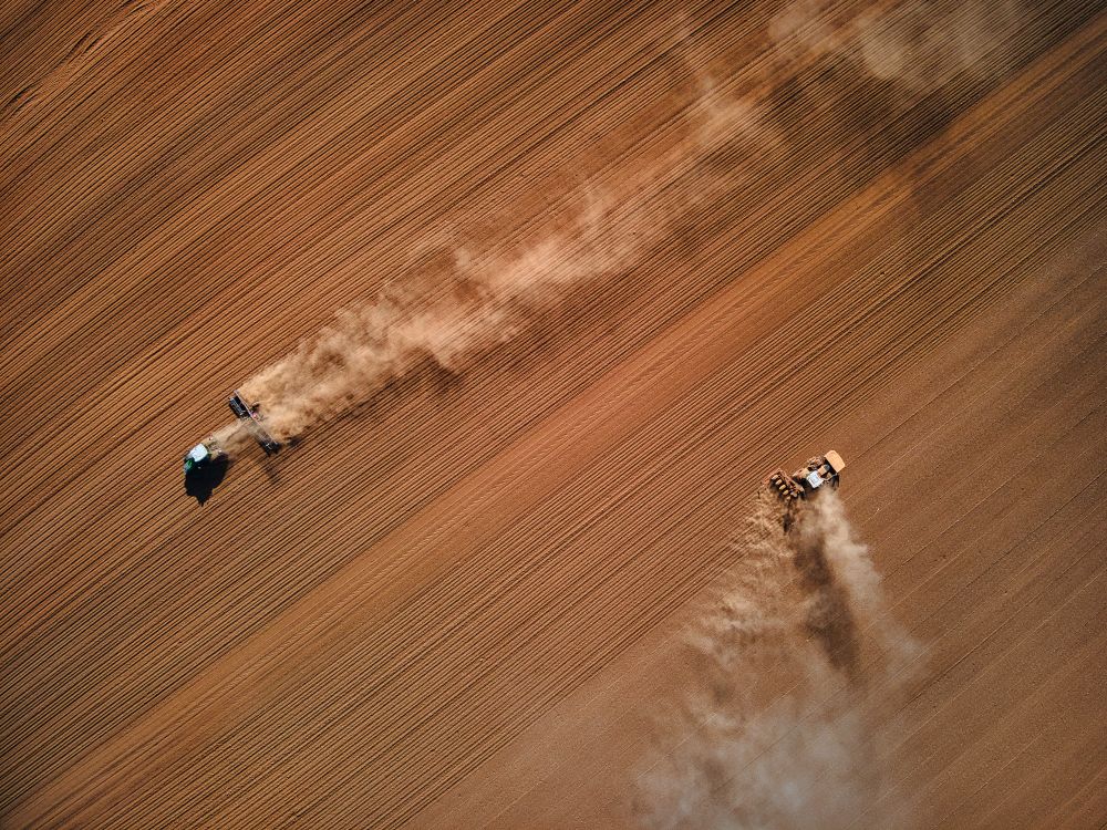 Top view of two workers flattening sand in desert