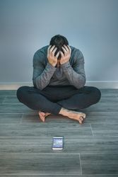 Man with problems sitting on the floor behind of his mobile